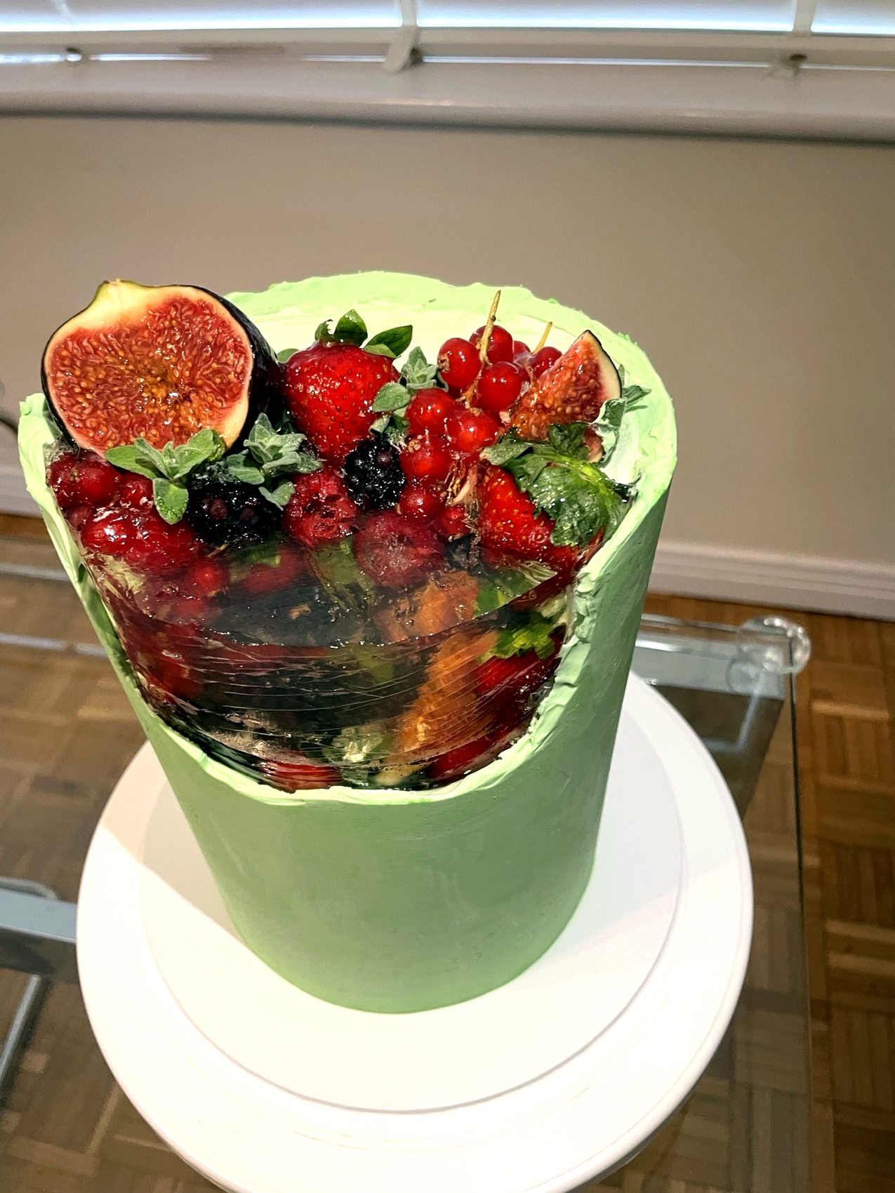 Tarta verde clara con flores frescas blancas, cardos azules y detalles dorados.