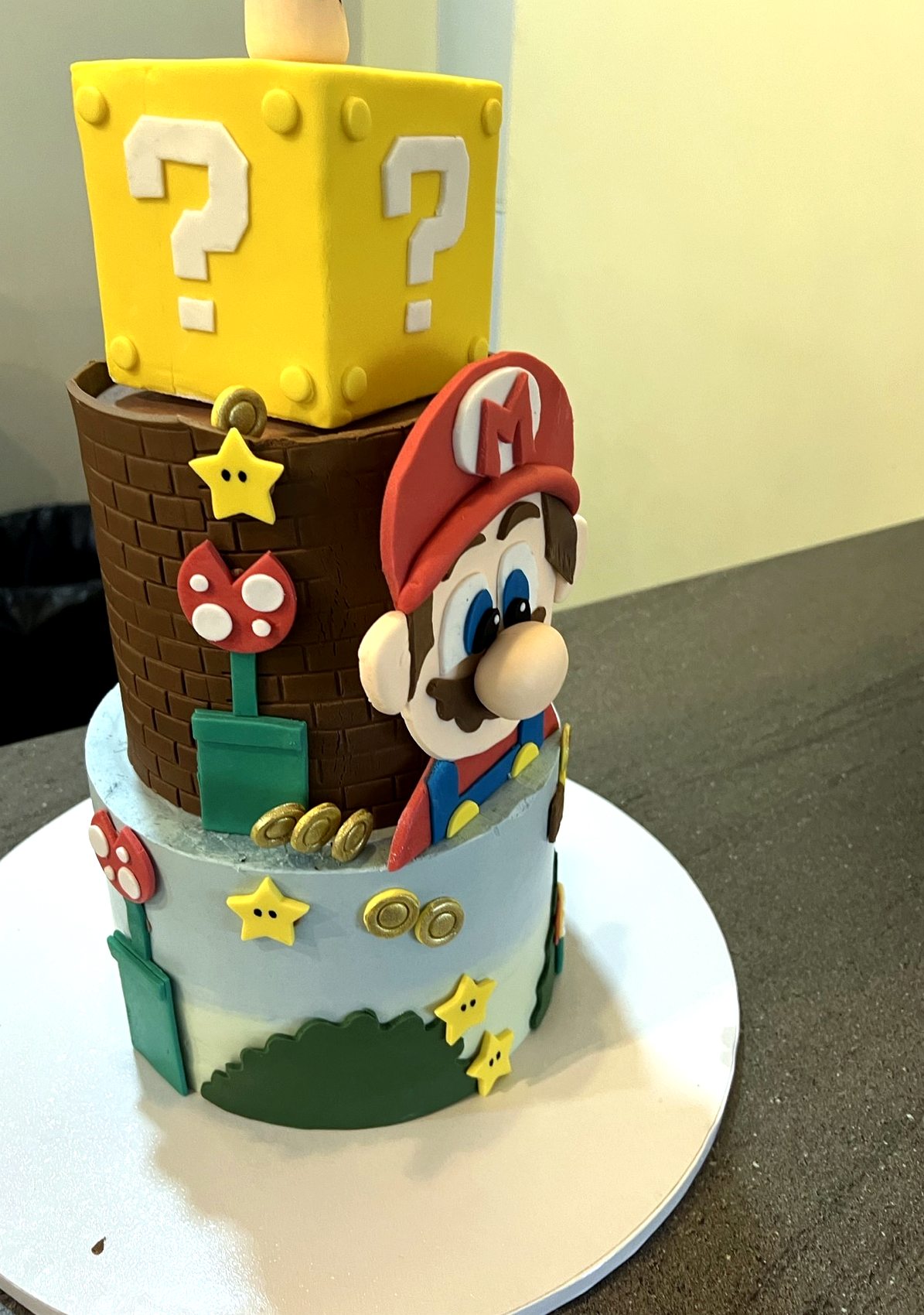 Tarta cuadrada amarilla de Mario con bloques de interrogacion, estrellas y personaje.