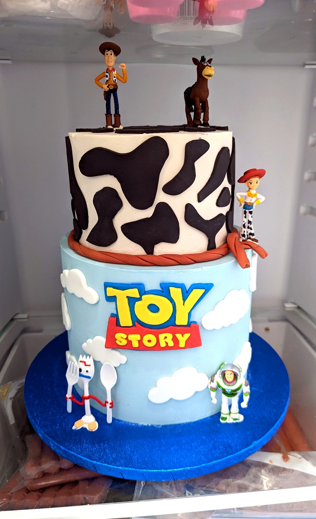 Tarta de Toy Story fotografiada en vitrina con niveles azul y estampado blanco y negro.