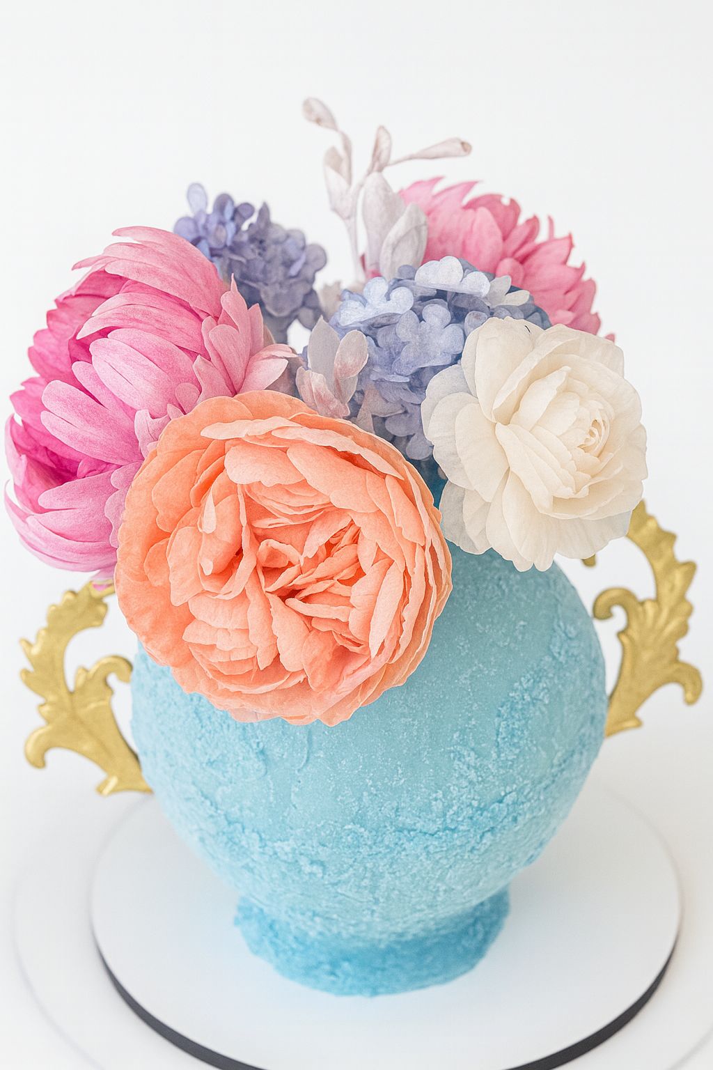 Tarta con forma de jarrón azul con un ramo de flores.