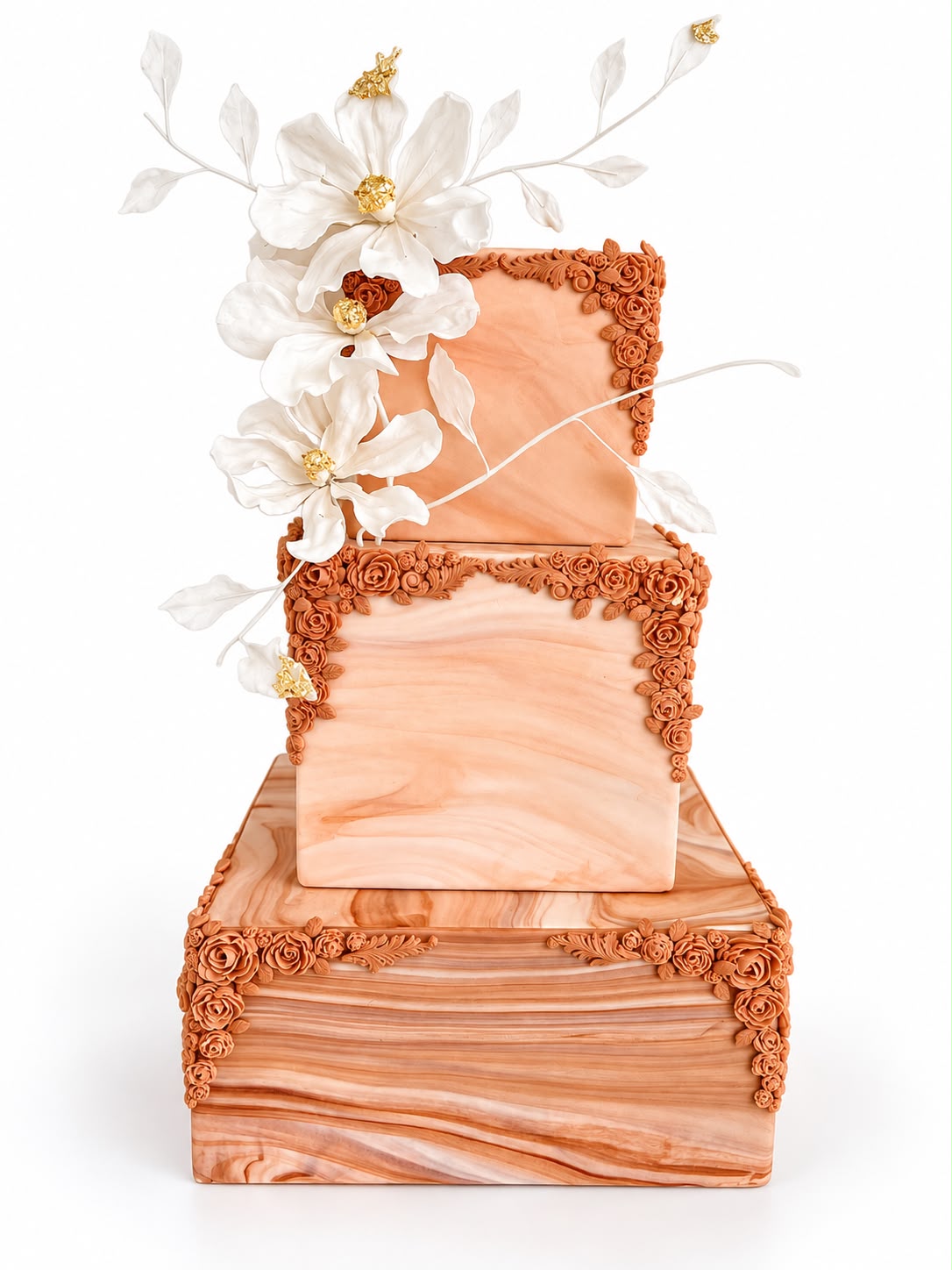 Tarta de tres pisos cuadrados en tono terracota, con flores blancas en lo alto.